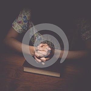 Woman hands praying with a bible, vintage tone