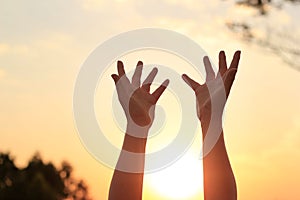 Woman hands praying for blessing on sunset background