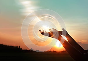 Woman hands praying on sunset background