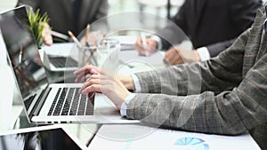 Woman hands pressing keys on a laptop keyboard in office.