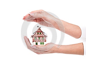 Woman hands protect little house on white