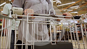 Woman hands push empty metal cart in supermarket. Shopping in grocery store