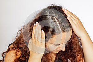 Woman hands pushing parting hair to sides showing graying hair roots on white background. Regrown roots which are in