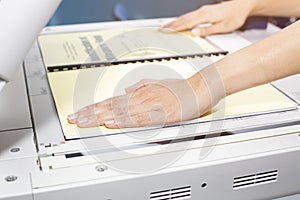 Woman hands putting a sheet of paper into a copying device