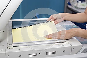 Woman hands putting a sheet of paper into a copying device