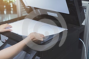 Woman hands putting a sheet of paper into a copying device