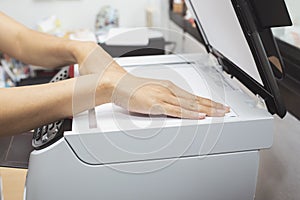 Woman hands putting a sheet of paper into a copying device or printer in the office