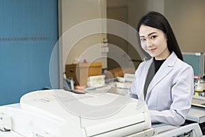 Woman hands putting a sheet of paper into a copying device or printer in the office