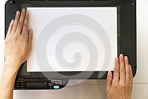 Woman hands putting a sheet of paper into a copying device or printer in the office