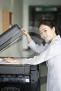 Woman hands putting a sheet of paper into a copying device or printer in the office