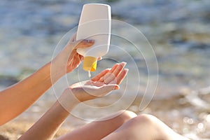Woman hands putting sunscreen from a bottle on the beach photo