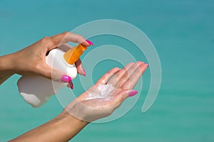 Woman hands putting sunscreen from a suncream bottle photo