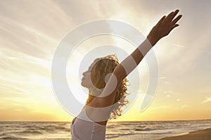 Woman With Hands Raised Meditating At Beach