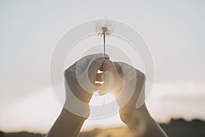 Woman hands raising up a dandelion flower against the sky. Nature and people lifestyle. Daydreaming and hope. Feeling and