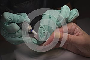 Woman hands receiving a manicure in beauty salon. Nail filing. Close up, selective focus