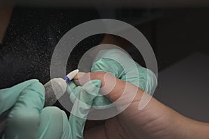 Woman hands receiving a manicure in beauty salon. Nail filing. Close up, selective focus