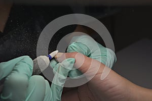 Woman hands receiving a manicure in beauty salon. Nail filing. Close up, selective focus