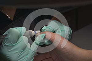 Woman hands receiving a manicure in beauty salon. Nail filing. Close up, selective focus