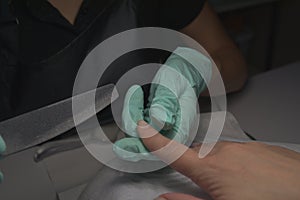 Woman hands receiving a manicure in beauty salon. Nail filing. Close up, selective focus