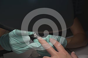 Woman hands receiving a manicure in beauty salon. Nail filing. Close up, selective focus