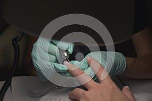 Woman hands receiving a manicure in beauty salon. Nail filing. Close up, selective focus