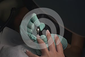 Woman hands receiving a manicure in beauty salon. Nail filing. Close up, selective focus