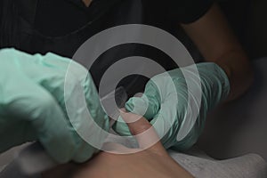 Woman hands receiving a manicure in beauty salon. Nail filing. Close up, selective focus