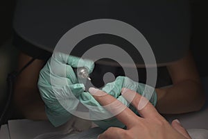 Woman hands receiving a manicure in beauty salon. Nail filing. Close up, selective focus