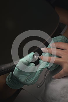 Woman hands receiving a manicure in beauty salon. Nail filing. Close up, selective focus