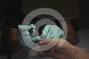 Woman hands receiving a manicure in beauty salon. Nail filing. Close up, selective focus