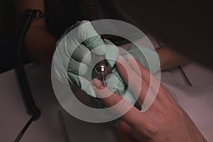 Woman hands receiving a manicure in beauty salon. Nail filing. Close up, selective focus