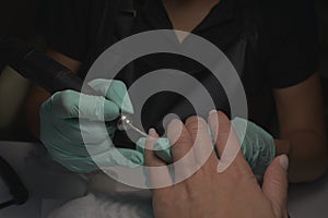 Woman hands receiving a manicure in beauty salon. Nail filing. Close up, selective focus