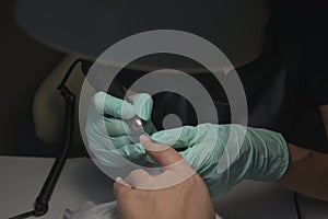 Woman hands receiving a manicure in beauty salon. Nail filing. Close up, selective focus