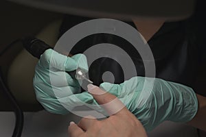 Woman hands receiving a manicure in beauty salon. Nail filing. Close up, selective focus