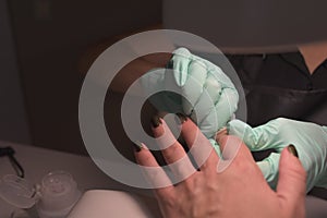 Woman hands receiving a manicure in beauty salon. Nail filing. Close up, selective focus