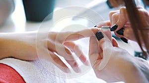 Woman hands receiving a manicure in beauty salon. Nail filing. Close up, selective focus.