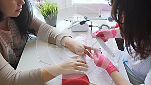 Woman hands receiving a manicure in beauty salon. Nail filing. Close up, selective focus.