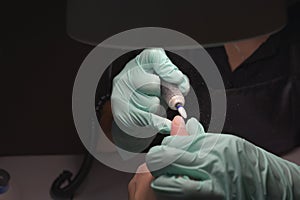 Woman hands receiving a manicure in beauty salon. Nail filing. Close up, selective focus