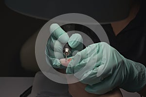 Woman hands receiving a manicure in beauty salon. Nail filing. Close up, selective focus