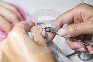 Woman hands receiving manicure and nail care procedure. Close up concept. Manicurist pushing cuticles on female's nails. female