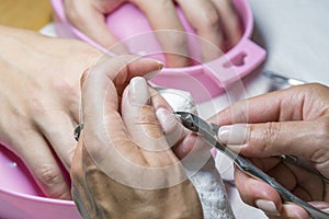 Woman hands receiving manicure and nail care procedure. Close up concept. Manicurist pushing cuticles on female's nails. female