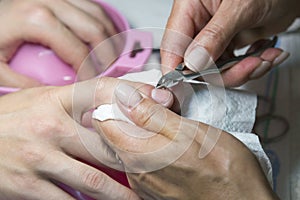 Woman hands receiving manicure and nail care procedure. Close up concept. Manicurist pushing cuticles on female's nails. female