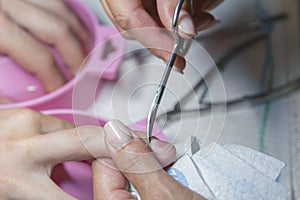 Woman hands receiving manicure and nail care procedure. Close up concept. Manicurist pushing cuticles on female's nails. female