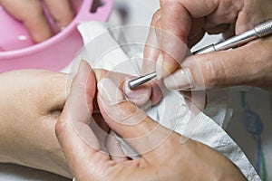 Woman hands receiving manicure and nail care procedure. Close up concept. Manicurist pushing cuticles on female`s nails. female