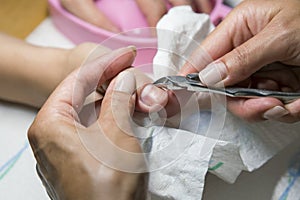 Woman hands receiving manicure and nail care procedure. Close up concept. Manicurist pushing cuticles on female`s nails. female