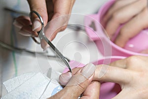 Woman hands receiving manicure and nail care procedure. Close up concept. Manicurist pushing cuticles on female`s nails. female