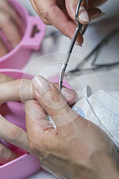 Woman hands receiving manicure and nail care procedure. Close up concept. Manicurist pushing cuticles on female`s nails. female