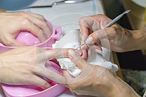 Woman hands receiving manicure and nail care procedure. Close up concept. Manicurist pushing cuticles on female`s nails. female