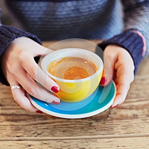 Woman hands with red manicure and cup of coffee