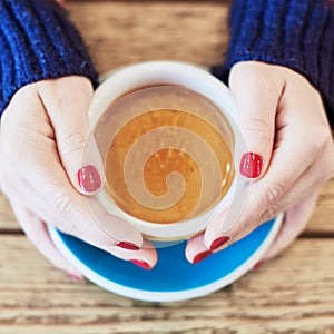 Woman hands with red manicure and cup of coffee